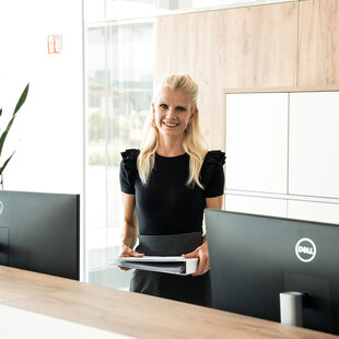 Eine elegant gekleidete Mitarbeiterin in der FRISTO Unternehmenszentrale in Buchloe, hält einen hellen Ordner in der Hand.