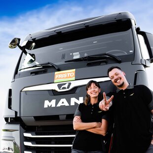 Eine Frau und ein Mann stehen in dunkler Arbeitskleidung vor einem LKW der FRISTO SE. Beide lächeln in die Kamera.