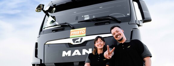 Eine Frau und ein Mann stehen in dunkler Arbeitskleidung vor einem LKW der FRISTO SE. Beide lächeln in die Kamera.